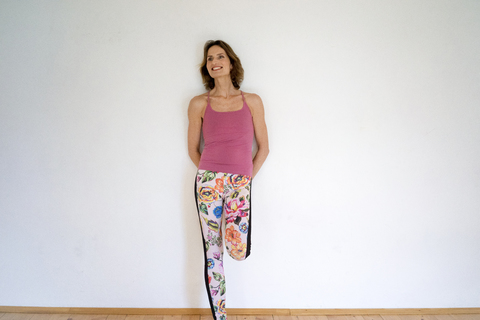 Smiling mature woman leaning against a wall stock photo