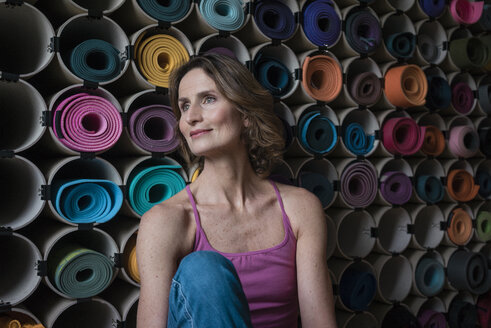 Smiling mature woman in front of assortment of yoga mats - MOEF00743