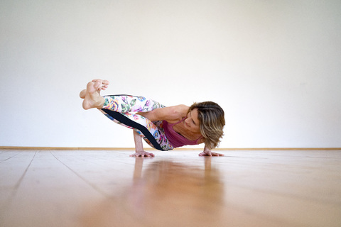 Reife Frau übt Yoga auf dem Boden in einem leeren Raum, lizenzfreies Stockfoto