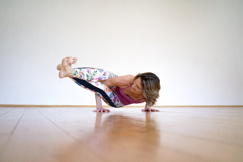 Reife Frau übt Yoga auf dem Boden in einem leeren Raum - MOEF00746