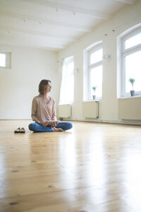 Reife Frau sitzt auf dem Boden in leeren Raum mit Tablet - MOEF00753