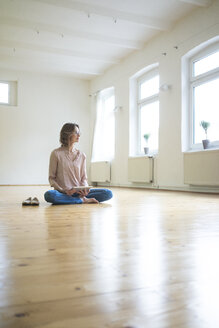 Mature woman sitting on floor in empty room with tablet - MOEF00753