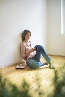 Mature woman sitting on floor using tablet - MOEF00759