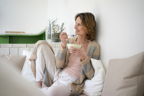 Relaxed smiling mature woman sitting on bench eating healthy food stock photo