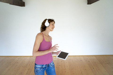 Mature woman listening to music in empty room stock photo