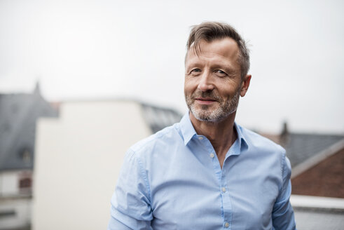 Portrait of smiling mature businessman on roof terrace - DIGF03281