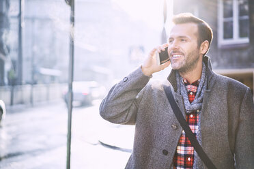 Portrait of smiling man on the phone in winter - BSZF00226