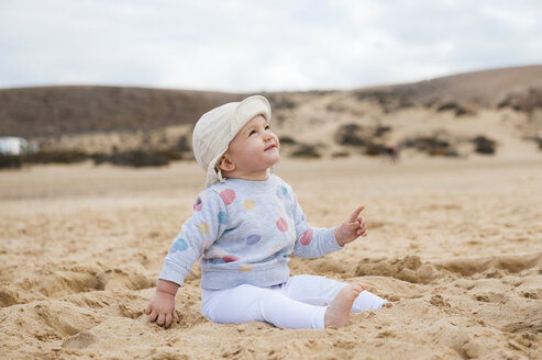 Spanien, Lanzarote, entspanntes kleines Mädchen sitzt am Strand und schaut nach oben - DIGF03285