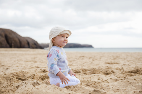 Spain, Lanzarote, content baby girl crouching on the beach stock photo