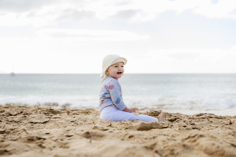 Spain, Lanzarote, laughing baby girl sitting on the beach stock photo