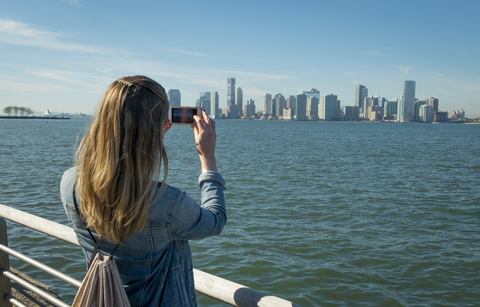 USA, New York, woman taking cell phone picture of New Jersey skyline stock photo