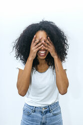 Porträt einer lachenden jungen Frau, die ihre Augen mit den Händen bedeckt - KIJF01899