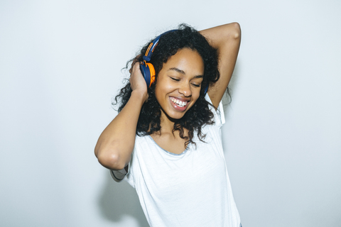 Porträt einer glücklichen jungen Frau, die mit Kopfhörern Musik hört, lizenzfreies Stockfoto