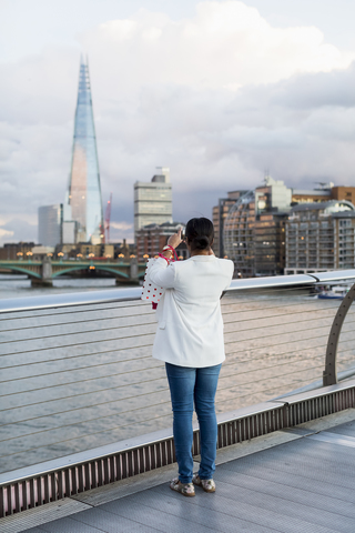 UK, London, woman standing on a bridge taking picture of The Shard stock photo