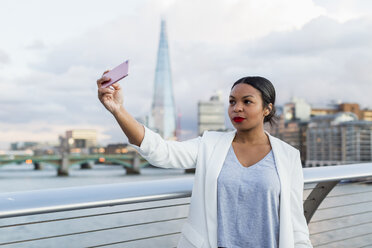 UK, London, Frau steht auf einer Brücke und macht ein Selfie - MAUF01347