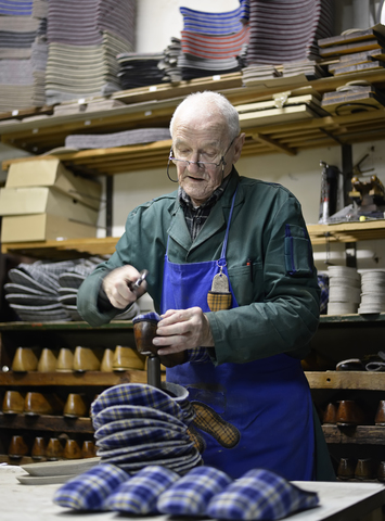 Senior shoemaker working on slippers in workshop stock photo