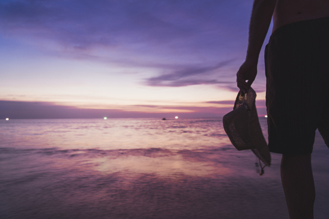 Thailand, Phuket, man standing at seaside by sunset, partial view stock photo