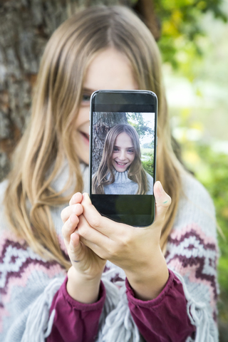 Portrait of laughing girl taking selfie with cell phone stock photo