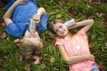 Boy and girl on a meadow having fun with tin can phone - SARF03560