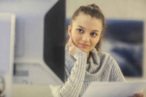 Porträt einer jungen Frau bei der Arbeit am Schreibtisch in einem Büro - SGF02172