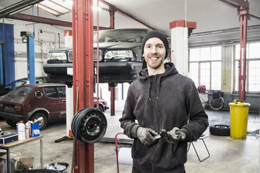 Porträt eines lächelnden männlichen Mechanikers in einer Autowerkstatt - FSIF00014