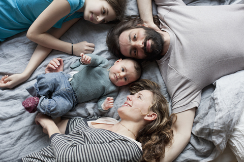 Blick von oben auf eine Familie, die sich auf einem Bett entspannt, lizenzfreies Stockfoto