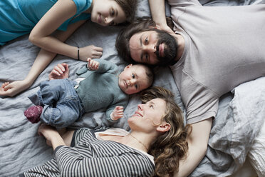 Blick von oben auf eine Familie, die sich auf einem Bett entspannt - FSIF00029