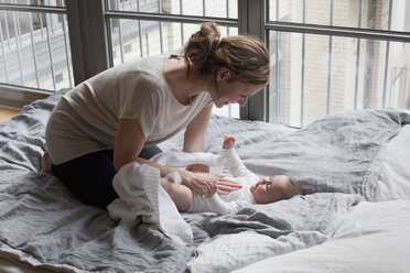 Mother playing with baby girl in bedroom - FSIF00033