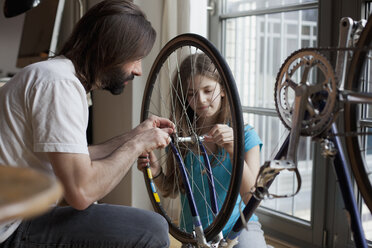 Vater und Tochter reparieren gemeinsam zu Hause ein Fahrrad - FSIF00035