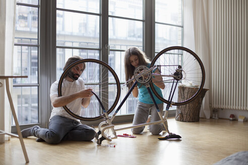 Vater und Tochter reparieren gemeinsam zu Hause ein Fahrrad - FSIF00038