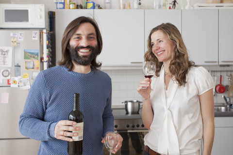 Glückliches Paar genießt Rotwein in der Küche, lizenzfreies Stockfoto