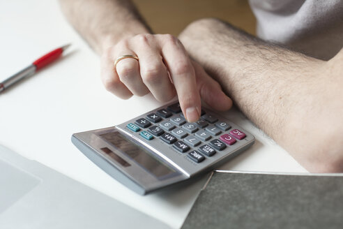 Ausgeschnittenes Bild eines Mannes, der einen Taschenrechner am Tisch benutzt - FSIF00055