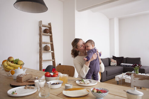 Liebevolle Mutter küsst ihr kleines Mädchen am Frühstückstisch - FSIF00059
