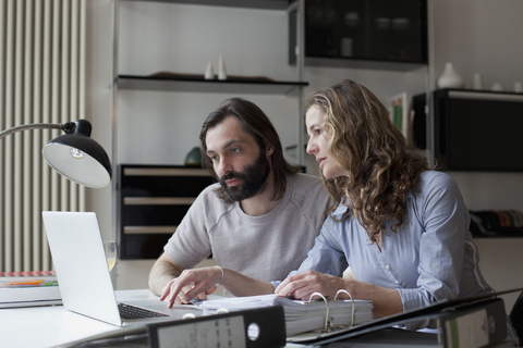 Mid adult couple working on laptop at home, lizenzfreies Stockfoto