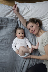 Hochwinkliges Porträt einer Mutter und eines kleinen Mädchens auf einer Matratze liegend - FSIF00071