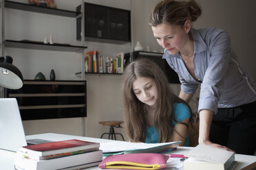 Mutter hilft Tochter bei den Hausaufgaben am Tisch - FSIF00078