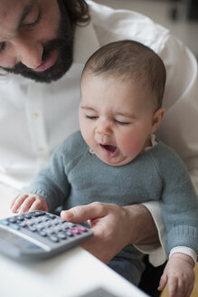 Süßes kleines Mädchen gähnt mit Vater, der zu Hause einen Taschenrechner benutzt - FSIF00090