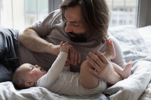 Affectionate father with baby girl in bedroom - FSIF00092