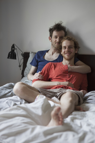 Porträt eines romantischen schwulen Paares, das sich zu Hause auf dem Bett entspannt, lizenzfreies Stockfoto