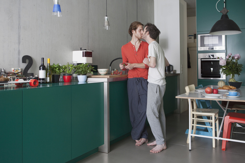 Romantisches schwules Paar küsst sich in voller Länge in der Küche, lizenzfreies Stockfoto