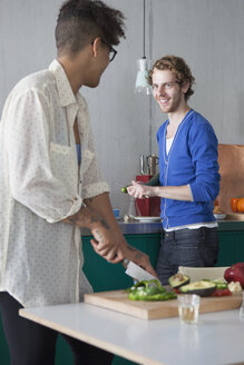 Lächelnder Mann, der mit seiner Freundin in der Küche Essen zubereitet - FSIF00202