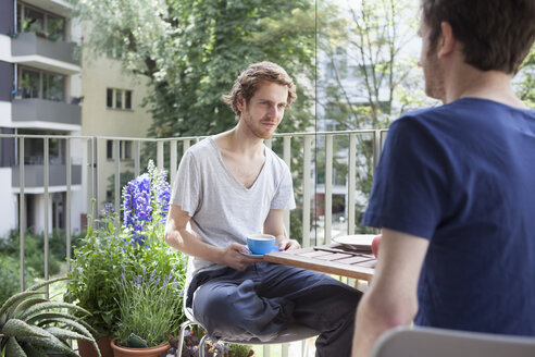 Schwuler Mann sieht seinen Partner an, während er auf der Veranda Kaffee trinkt - FSIF00203