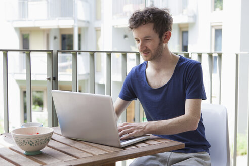 Junger Mann benutzt Laptop auf Veranda - FSIF00207