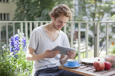 Smiling man using digital tablet at porch - FSIF00215