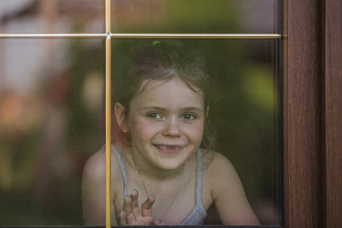 Happy little girl looking out through window - FSIF00239