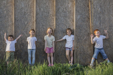Porträt von verspielten Kindern, die im Park an der Wand stehen - FSIF00242