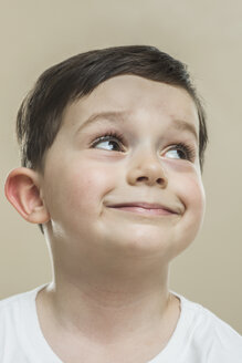 Close-up of cute boy smiling against beige background - FSIF00251