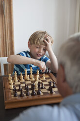 Little boy playing chess with grandfather at home - FSIF00271