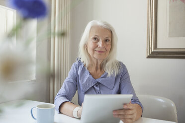 Porträt einer selbstbewussten älteren Frau, die ein digitales Tablet in der Hand hält - FSIF00291