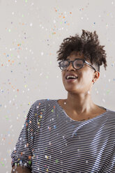 Happy young woman looking at confetti flying at home - FSIF00298